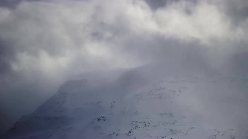 Clouds passing through a snowy mountain top
