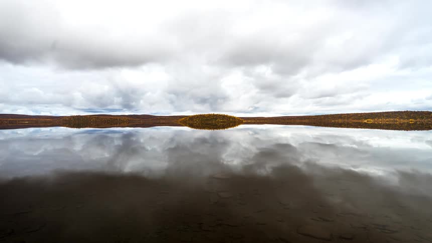 The water of a lake is reflecting the clouds in the sky