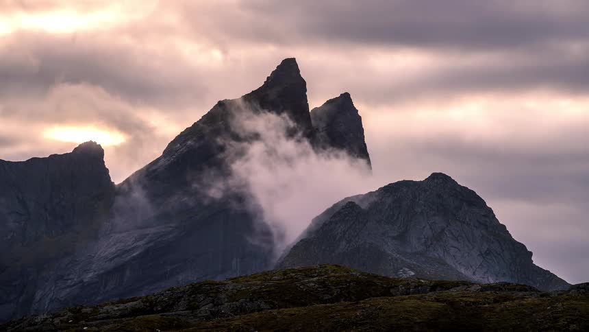 The clouds flow over the mountain peak
