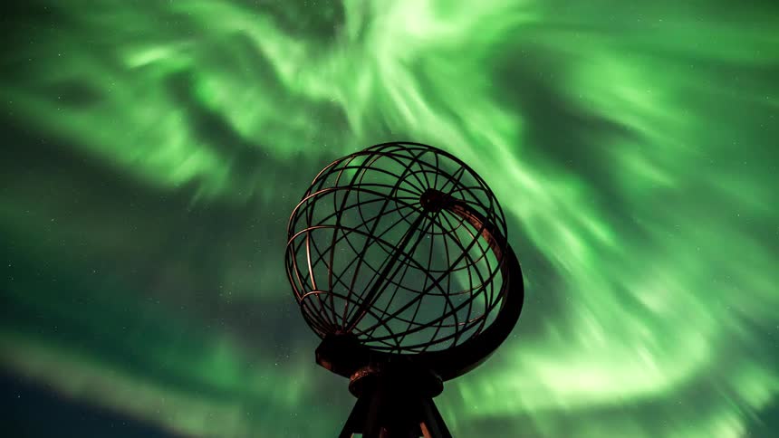 Steel globe at north cape with northern lights