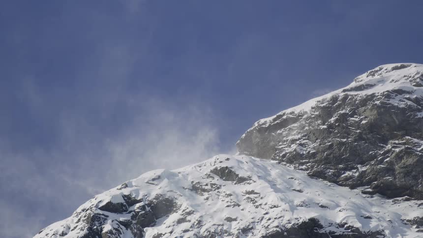 A mountain peak covered in snow and a little fog