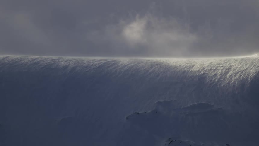 Landscape of a mountain with snow flying on a sunny day