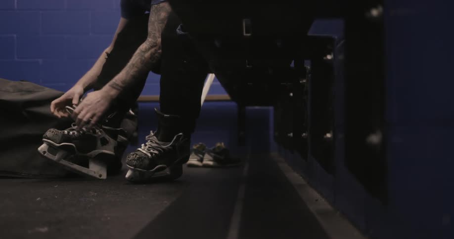 A person laces up their ice skates