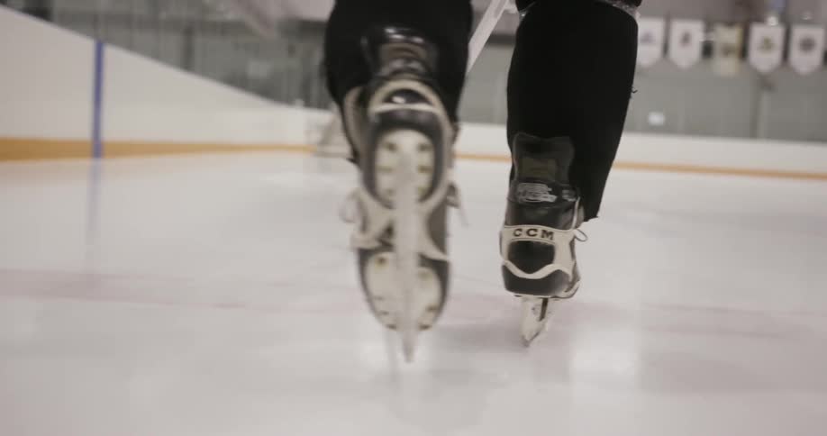 A person ice skating leads a puck toward a goal