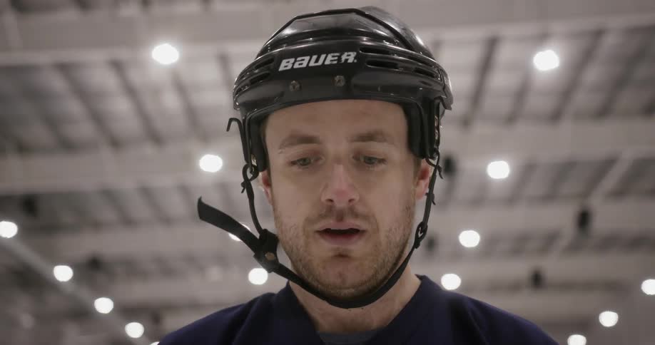A hockey player standing in an arena is thinking