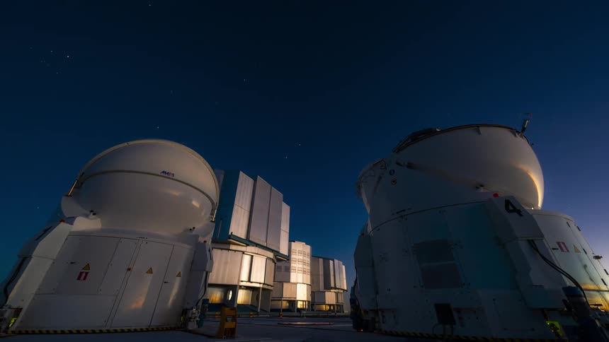 Two telescopic antennas pointed at a sky in timelapse with a dawning day