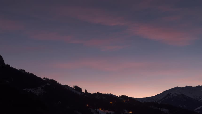 Clouds move across the sky over mountainous terrain