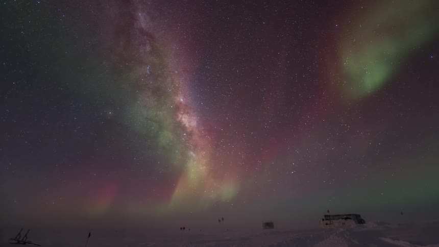 Aurora Australis shining above a research station and under a starry sky