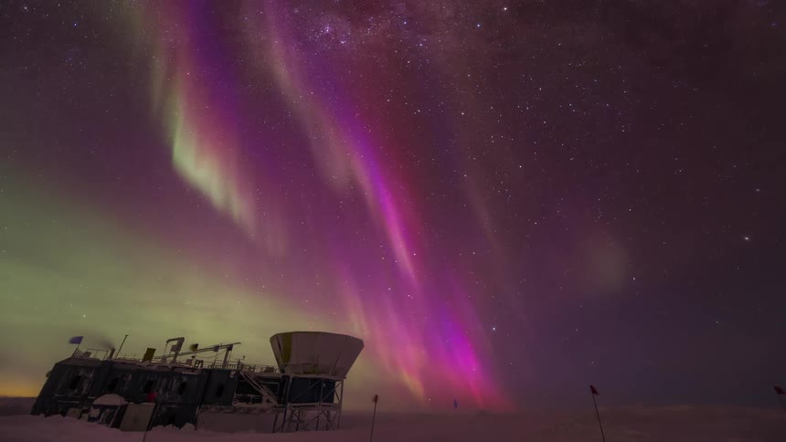 observatory at the south pole with with greenish and purple Aurora Australis