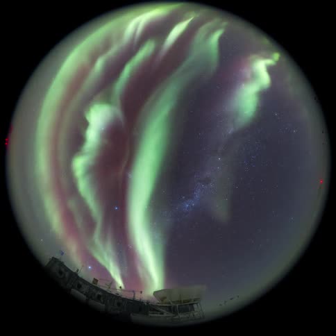 fisheye view of aurora filling the night sky over an observatory