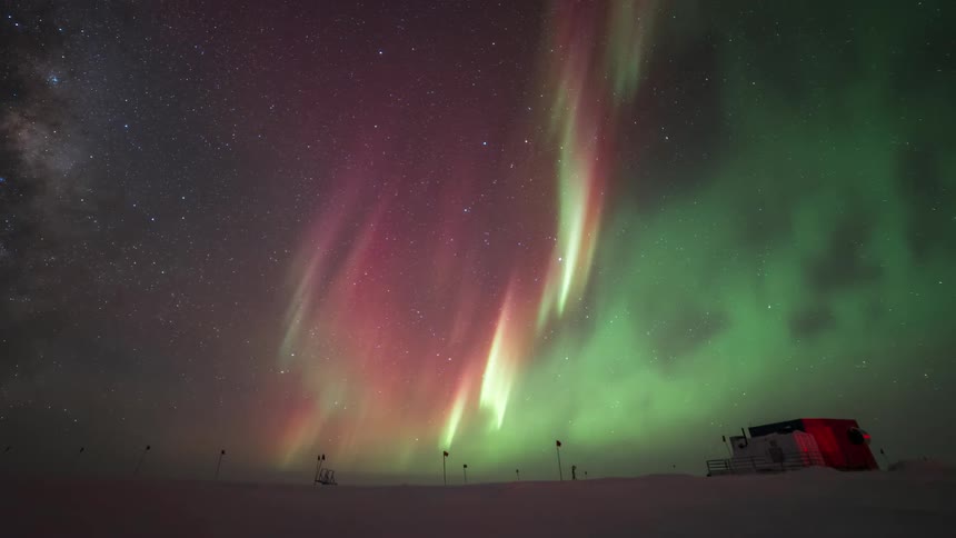 The aurora shines over the people walking in the snow