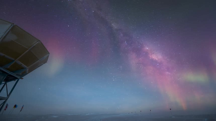 An aurora in the sky at dawn near an observatory antenna