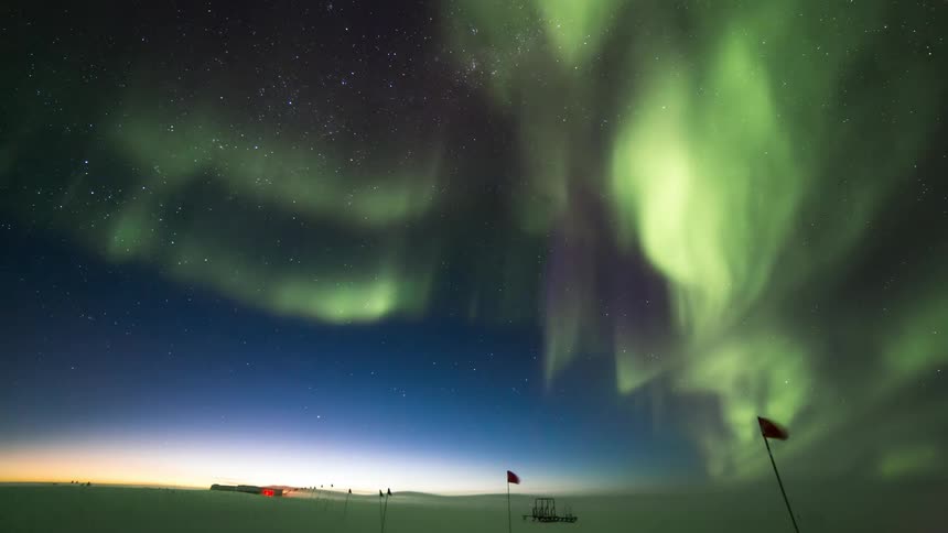 Aurora Australis over a snowy field marked with flags