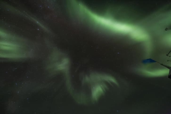 The Aurora Australis glows among the stars in the sky