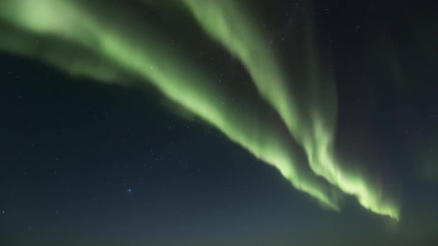 A green aurora roils in the sky