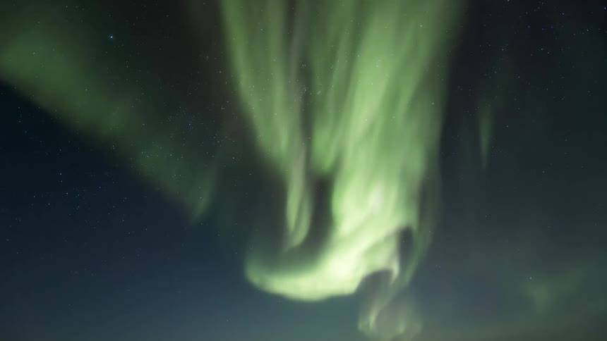A dark night sky has a green Aurora Australis moving around it
