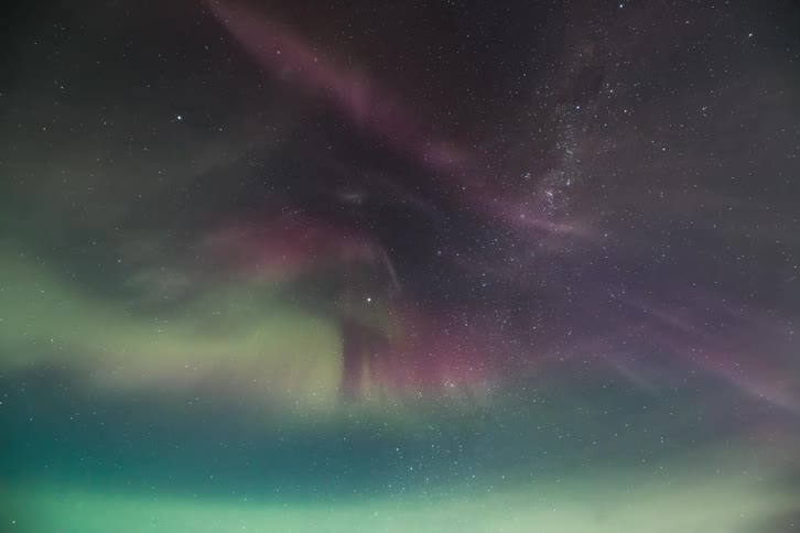 Aurora Australis shining with green and purple lights in the sky during the starry night