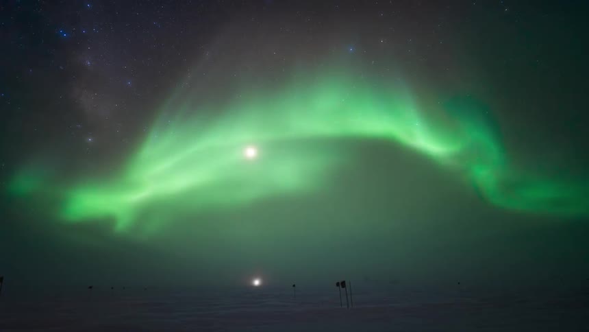 The green glow of the Aurora Australis in the sky in a region with snow on the ground