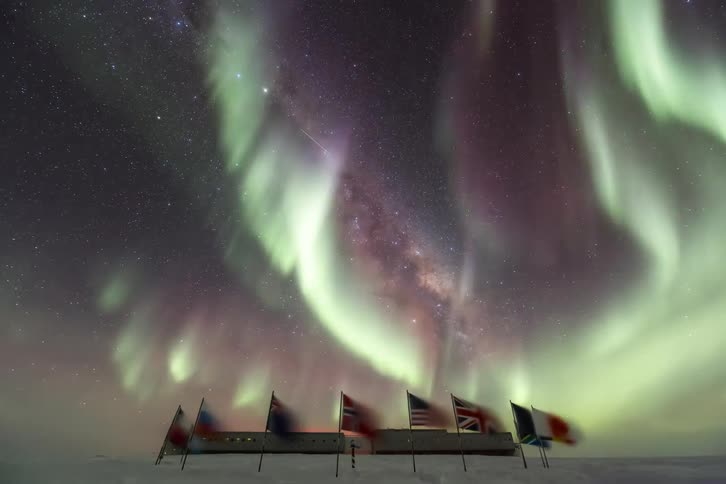 Flags of different countries around the south pole with a nightsky with Aurora Australis