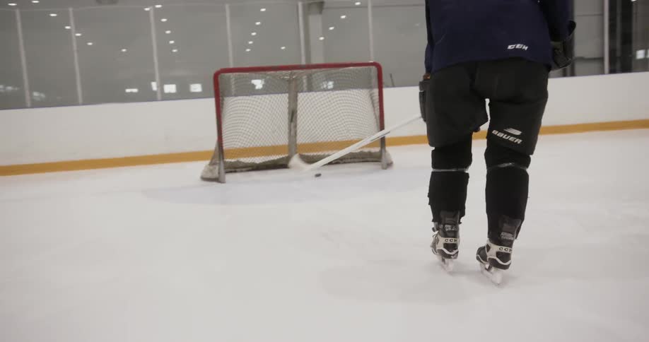 Man hitting hockey puck into goal