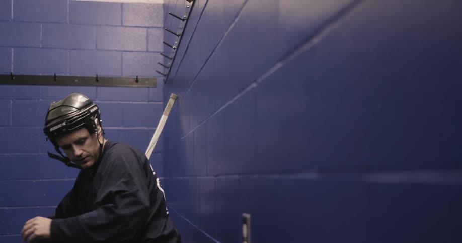 A hockey player straps up his helmet