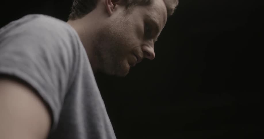 Man in gray t-shirt stroking something out of view