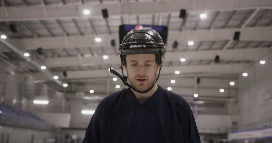 Man wearing helmet in stadium standing and staring downwards