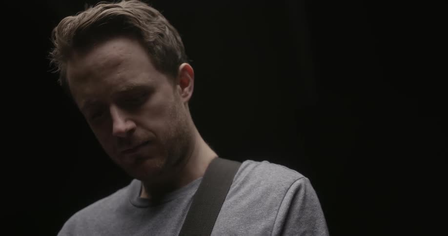 A man nods his head with a strap over his shoulder