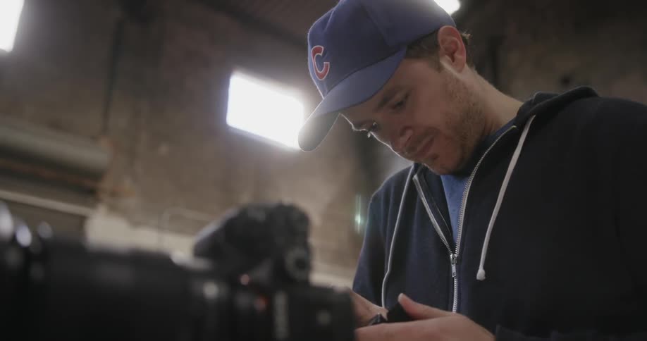 A man in a blue hat adjusts something in his hands