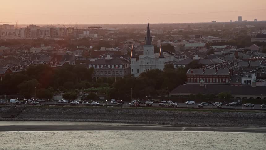 Vehicles line street between church and coast a distance from skyline under a red sky