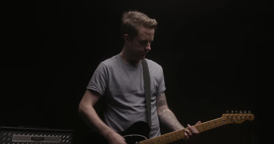 A guitarist strums on a fender telecaster guitar