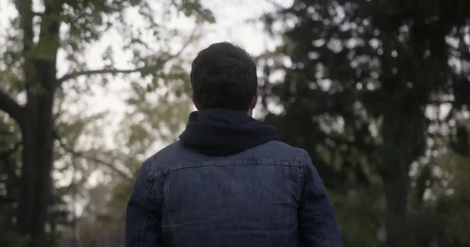 A man wearing a denim jacket walks down a trail