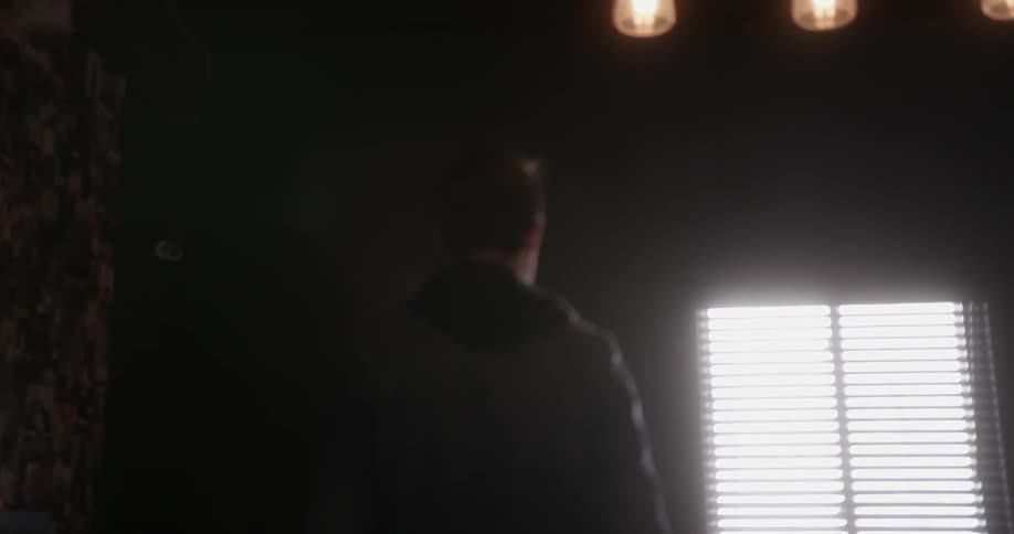 A man wearing a denim jacket turns on lights inside