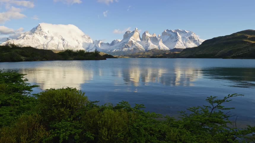 A lake surrounded by forests and mountains during the day