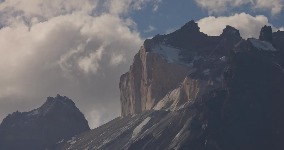 Clouds flow through sky over foggy mountains partially covered by snow