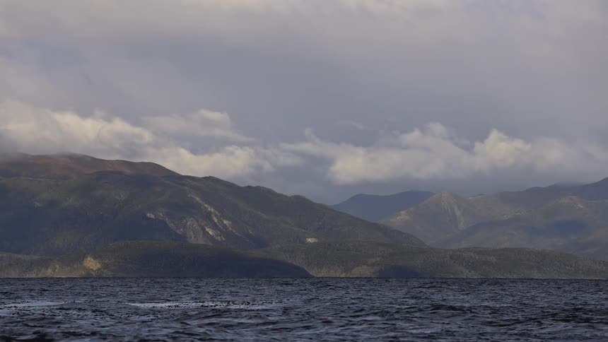 View of a vast body of water with mountains in the background under a cloudy sky