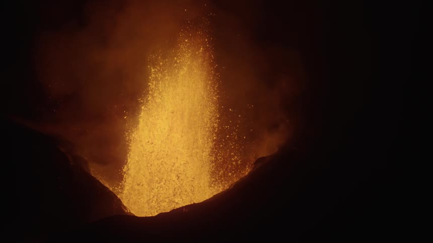 A volcanic eruption with bright lava and ash against a dark background