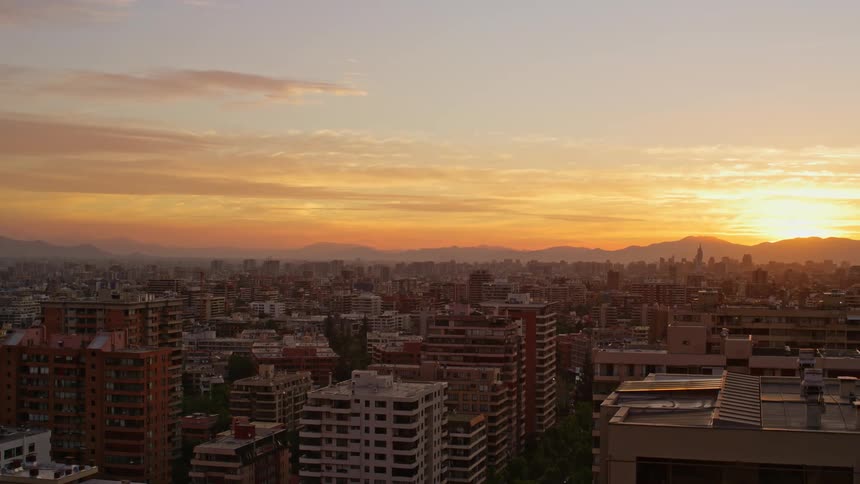 A city with high and low buildings on a morning with the orange sun on the horizon
