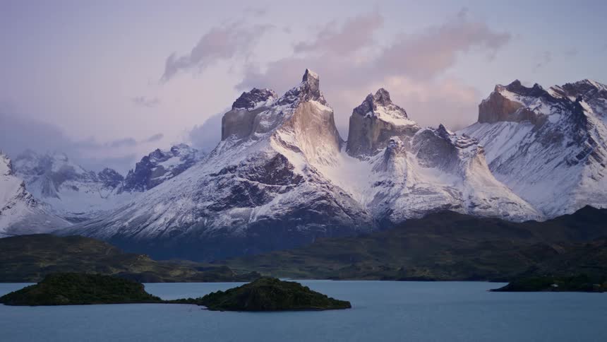 Aerial of a snowy mountain range surrounded by a lake