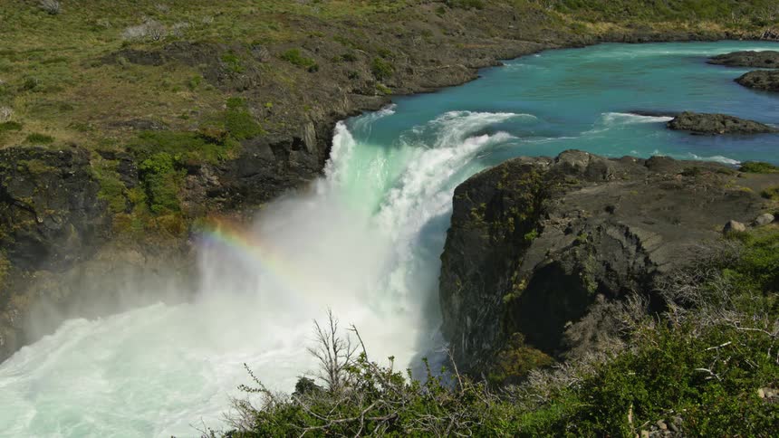 A waterfall with a rainbow in the mist flowing from a river