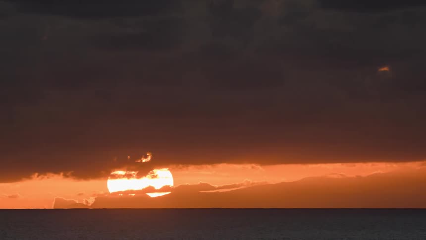 A time lapse shows the rising sun peaking through dense clouds