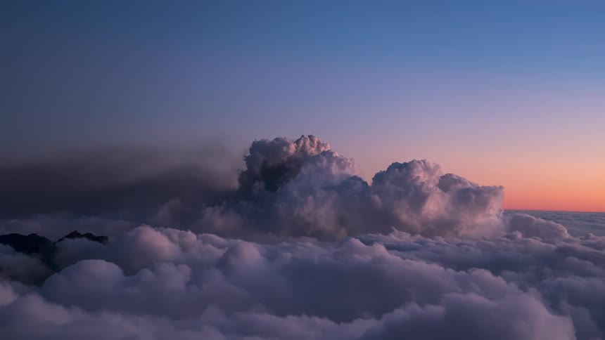 Smoke and ash from a volcanic eruption break the cloud layer over the mountains