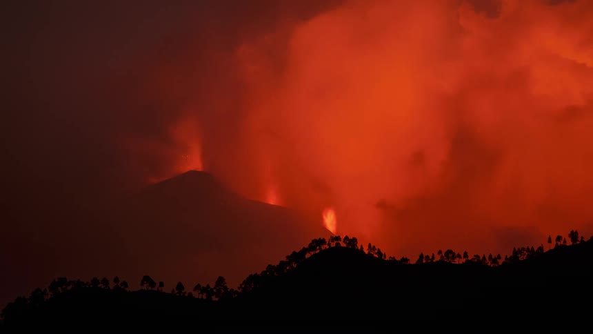 Time lapse of a volcanic eruption with bright lava and ash against a dark background
