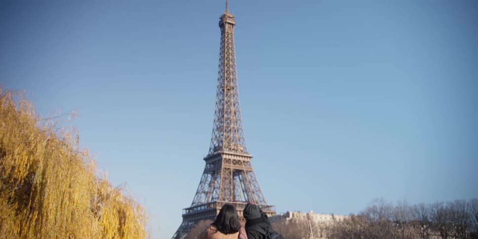 A couple point to the eiffel tower