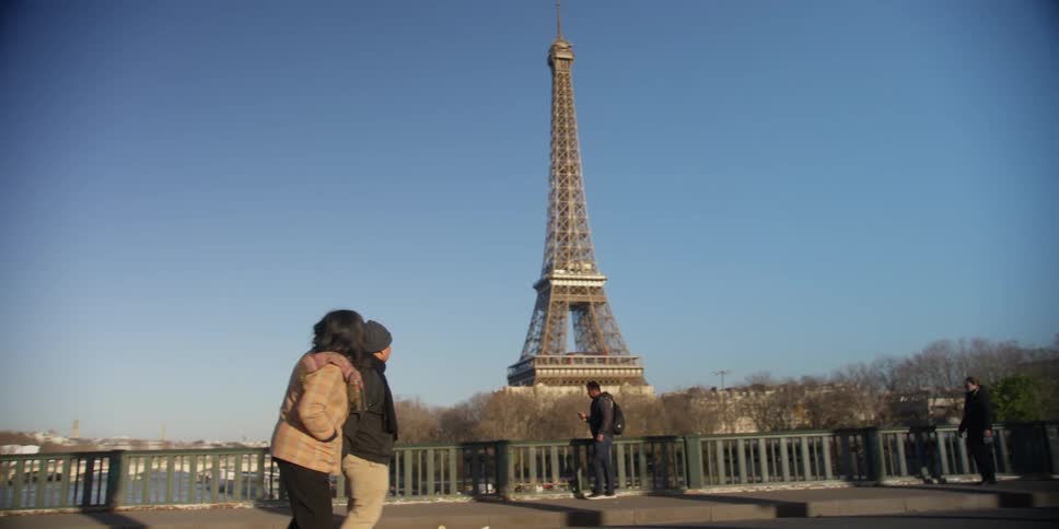 A couple visiting paris look at the eiffel tower