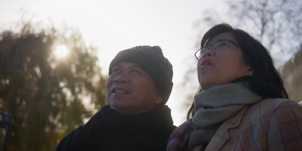 Two asian people talk and look into the distance