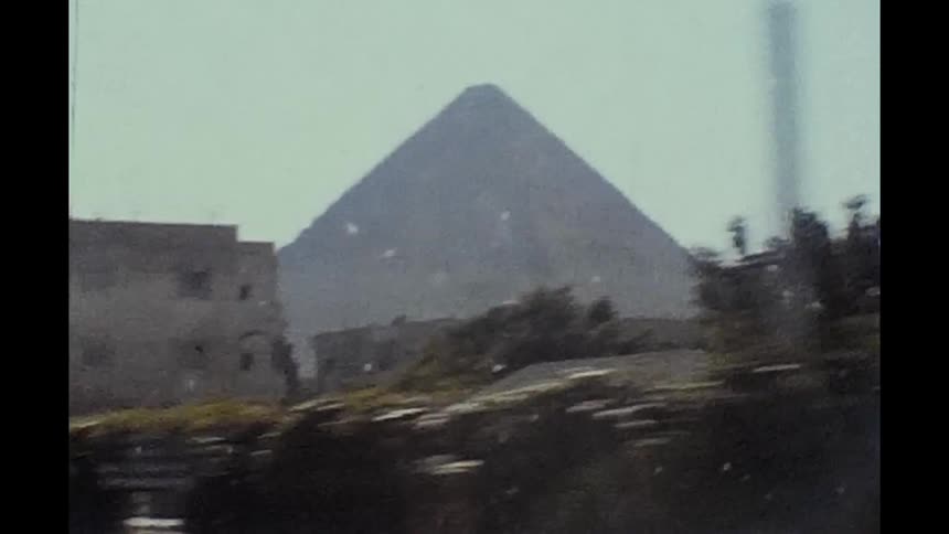 An egyptian pyramid seen behind a building