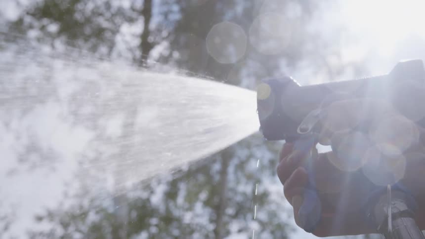 A man sprays water out of a garden hose