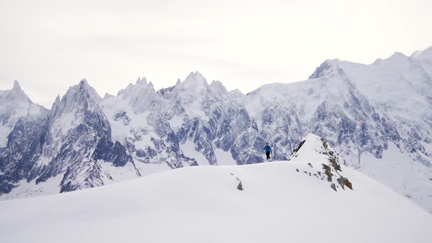 A person is hiking through a snow covered mountain range