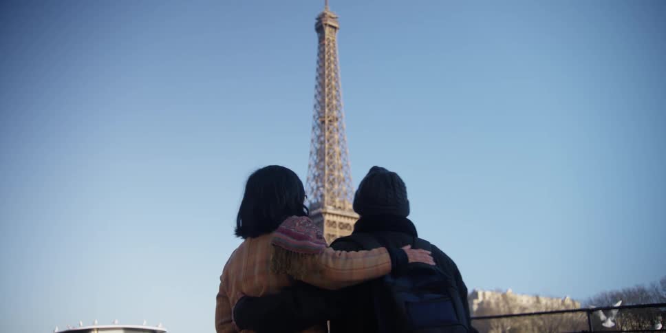 A couple hugs each other while gazing upon the eiffel tower